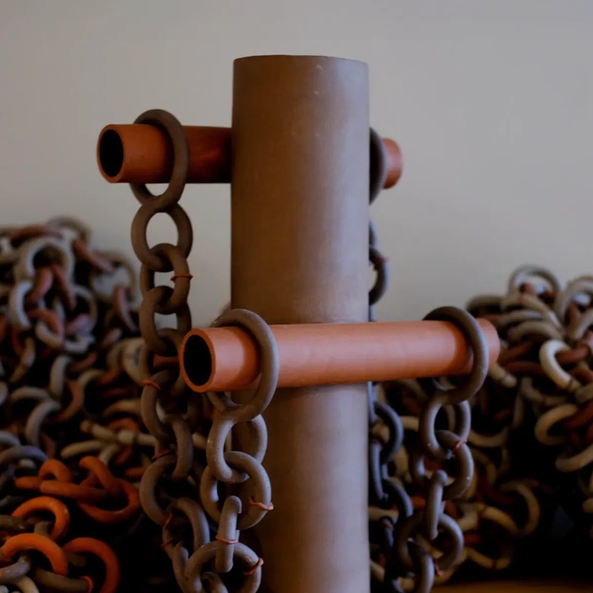 Close-up of a cylindrical vase with chains wrapped around it against a blurred background.